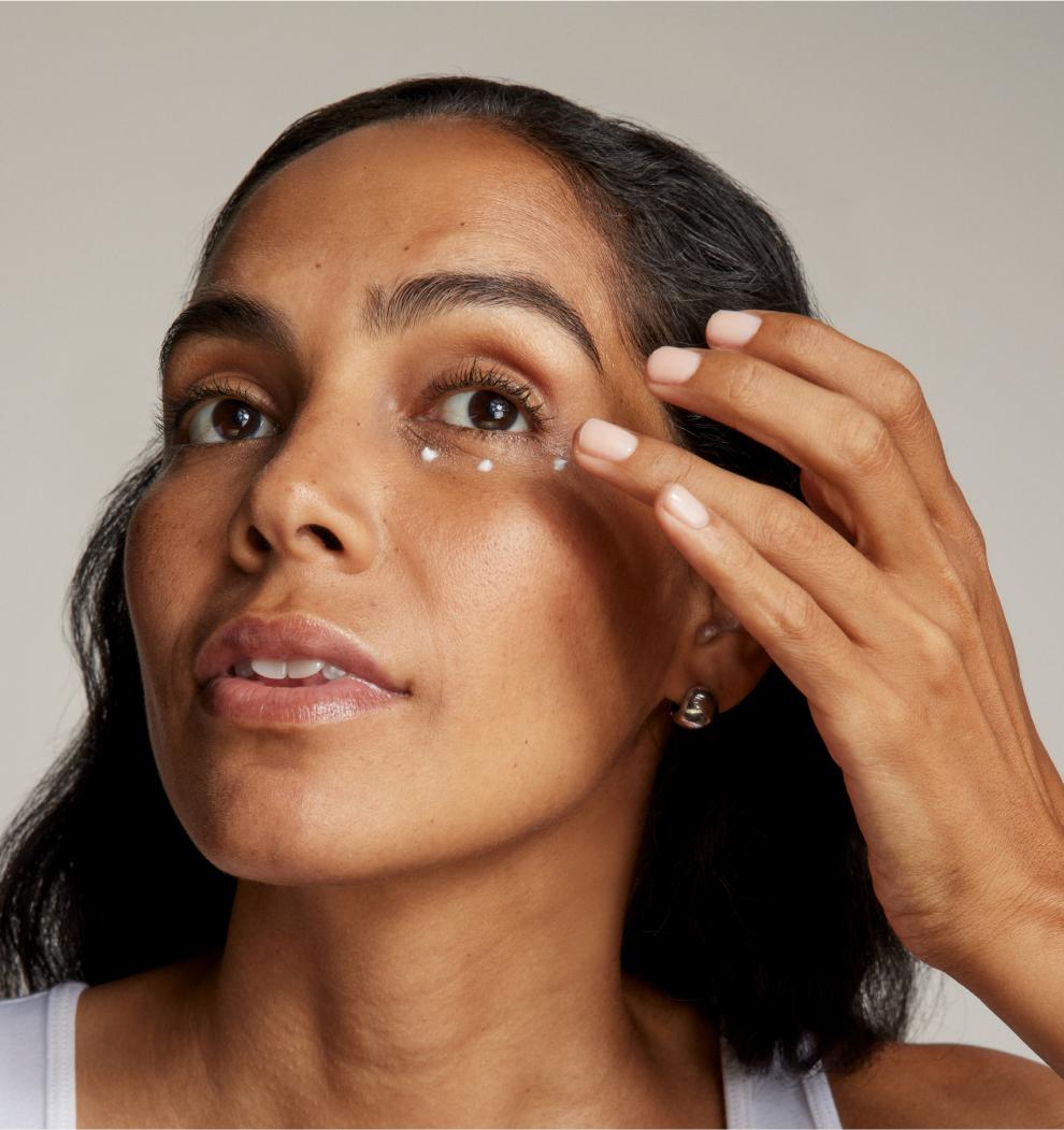 A close-up image of a woman with 3 dots of Eye Formula applied to her under-eye area