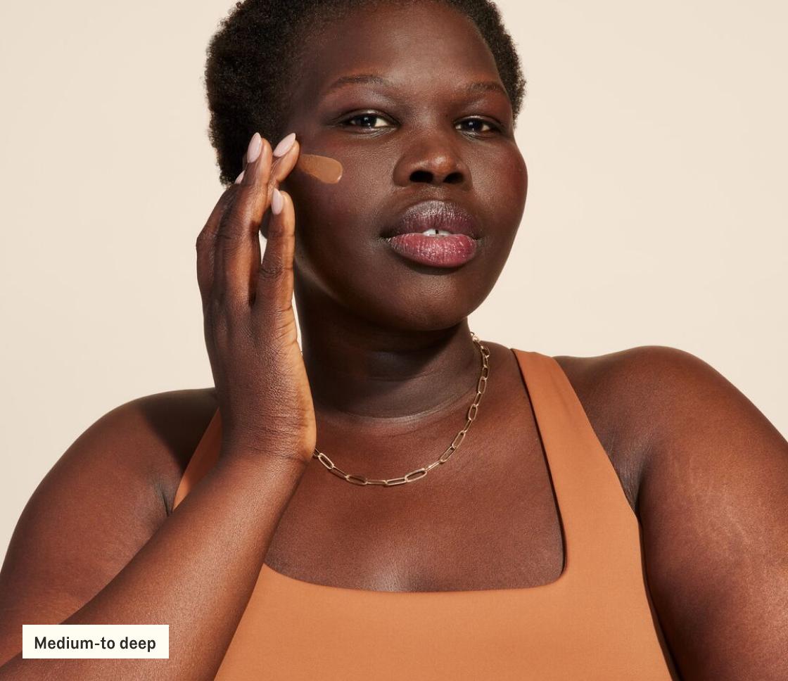 Woman applying SilkScreen to face (medium-to-deep)
