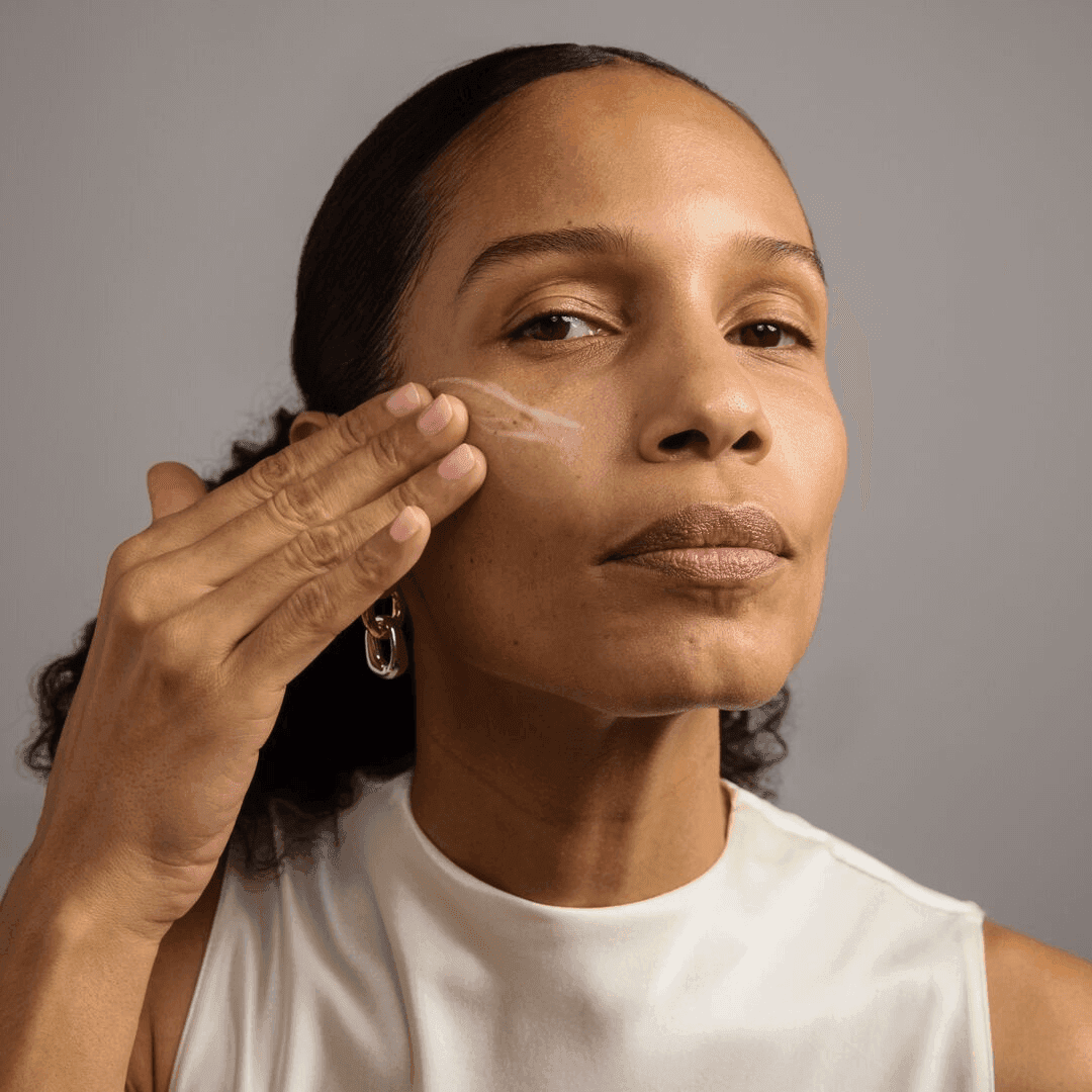 Woman applying cream to her face